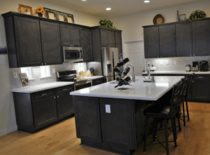 Above the cabinet decorations, like rooster plates, flowers, wine bottles, baskets, and more.