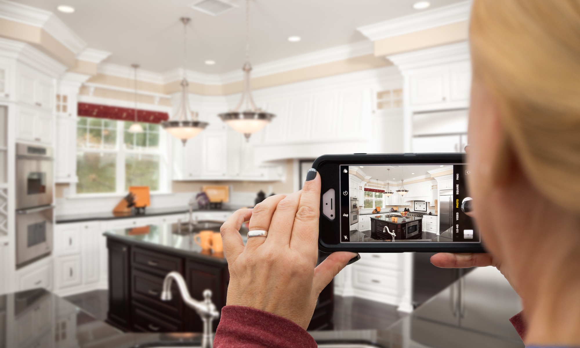 Woman Taking Pictures of A Custom Kitchen with Her Smart Phone.